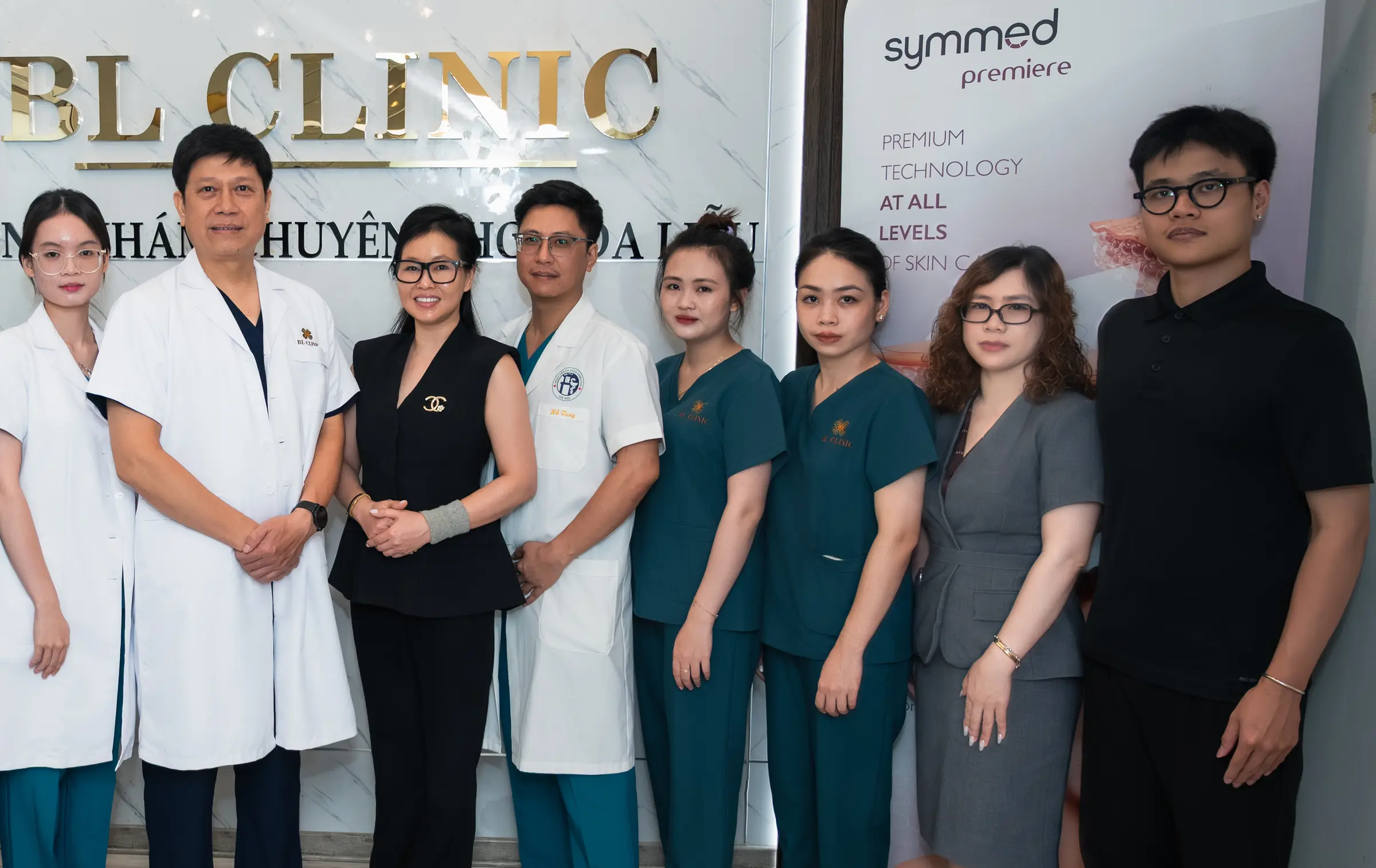 Đội ngũ bác sĩ và nhân viên BL Clinic trước tường logo phòng khám